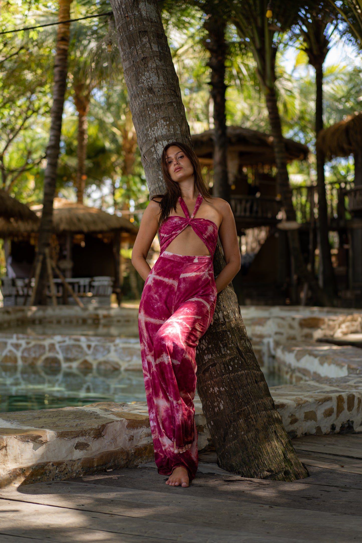 MOSS The Label pink tie-dye jumpsuit with halter neck and cutout details worn by model outdoors