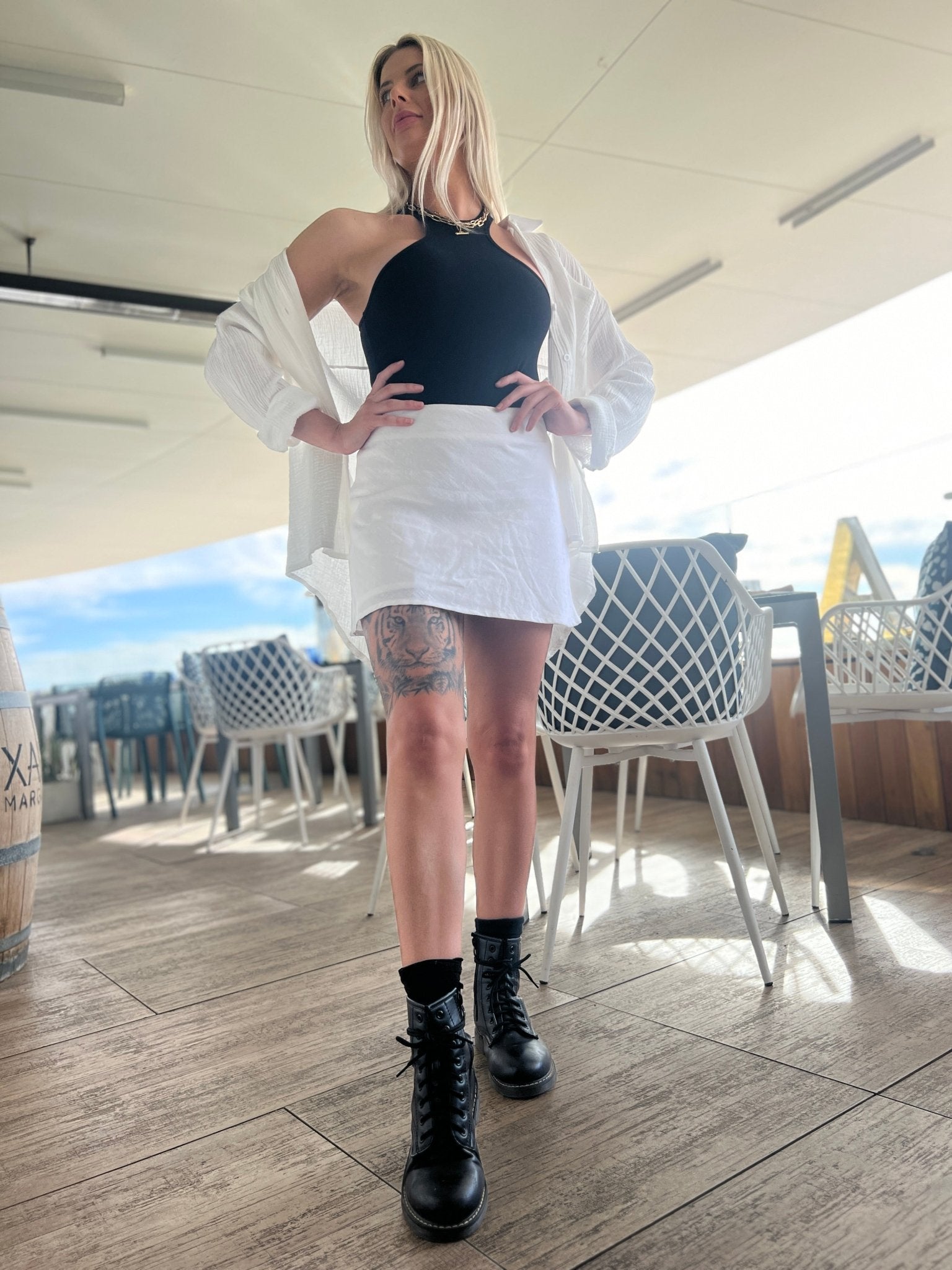 MOSS The Label black halter neck bodysuit worn with white skirt and open white shirt styled with black combat boots